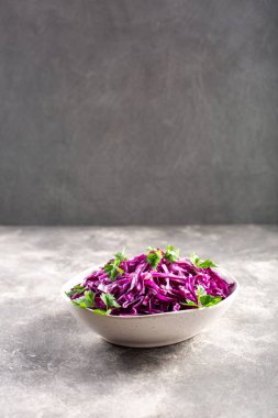 Beton arka planda kırmızı lahana salatası olan bir kase..