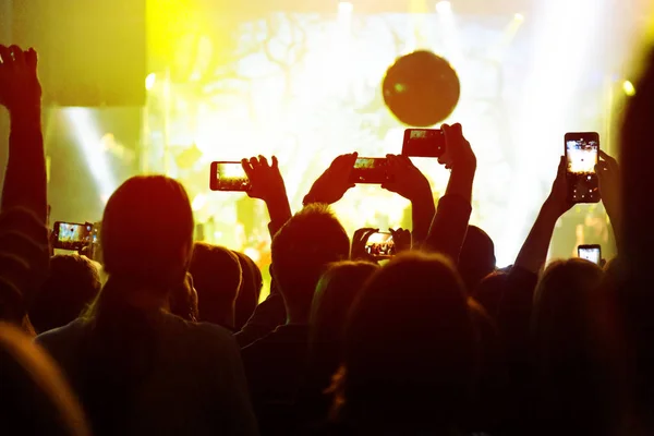 Los espectadores graban vídeo en un smartphone en un concierto . — Foto de Stock