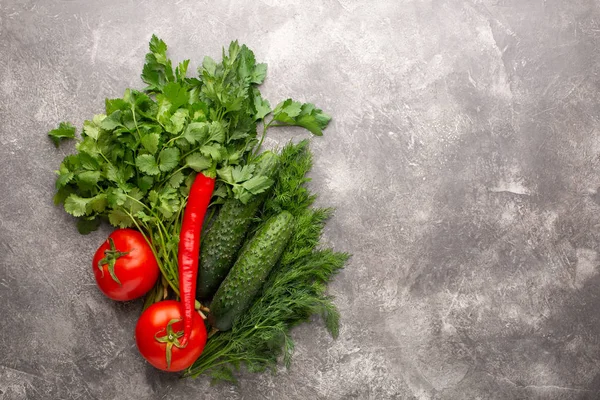 Verschillende verse groenten, tomaten, komkommers en chili op een grijze betonnen ondergrond. — Stockfoto