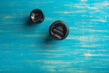 Mavi ahşap arka planda iki farklı boyutta tek kullanımlık kahve fincanı..