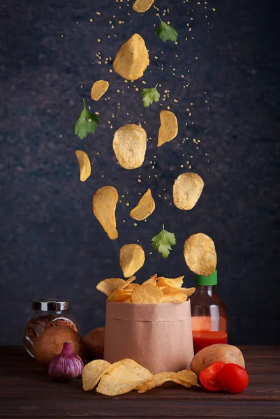 悬浮的薯片 土豆片和西红柿掉进木桌的工艺袋里 — 图库照片