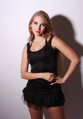 Küçük siyah elbiseli, çok uzun sarı saçlı, güzel moda saksocu kız. Sert gölgeli beyaz duvarın yanında kal.