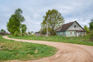 Yaz aylarında yeşil bir ev ile bir toprak yol