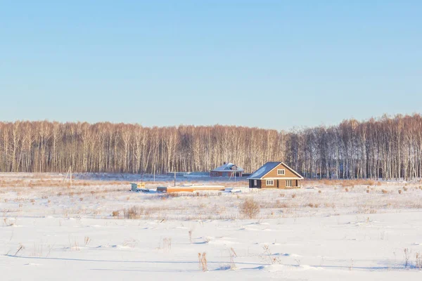 Casas en un campo nevado en un día soleado — Foto de Stock