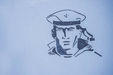 Savaş anıtındaki bir denizci resmi, gri bir duvarda.