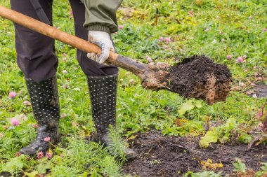 Kauçuk çizmeli bir adamın elinde dünyayı kürekle.