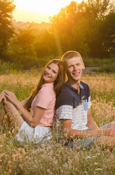 Happy loving couple sitting on a field — Stock Photo, Image