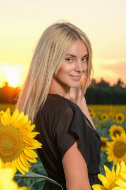 portre ayçiçeği tarlası üzerinde siyah elbiseli güzel genç sarışın model
