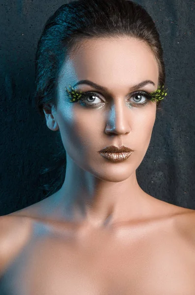 Retrato de belleza de una mujer con una pluma de pestañas verde grande falso —  Fotos de Stock