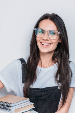 Kameraya bakarak ve kitap tutan gülümseyen beyaz öğrenci portresi