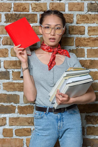 Stilvolle asiatische Mädchen mit Büchern und Blick auf die Kamera — Stockfoto