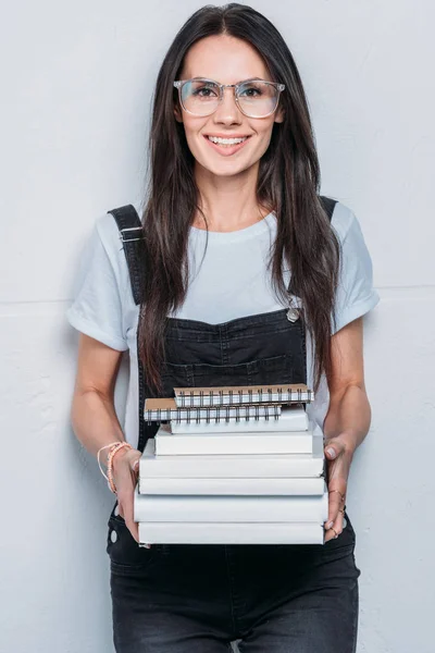 Retrato de estudante caucasiano sorridente segurando livros e olhando para a câmera — Fotografia de Stock