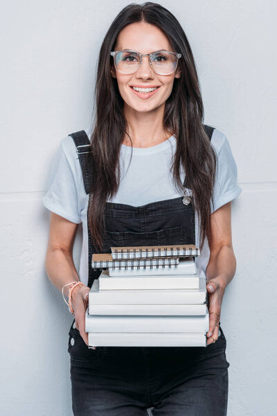 portrait of smiling caucasian student holding books and looking at camera