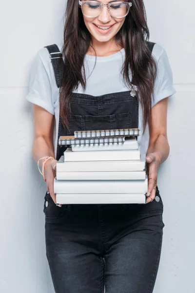 Jovem mulher branca sorridente em óculos segurando livros — Fotografia de Stock