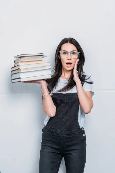 Asombrado estudiante caucásico sosteniendo libros con expresión facial —  Fotos de Stock