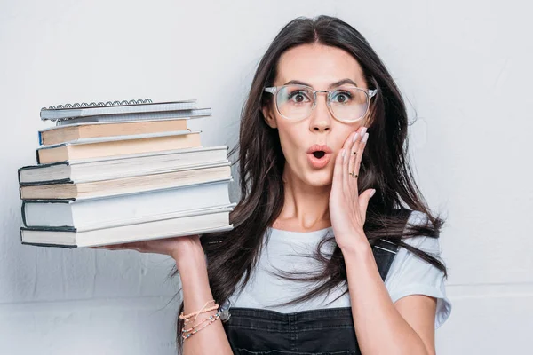 Portrait of astonished caucasian student holding books with facial expression — Stock Photo, Image