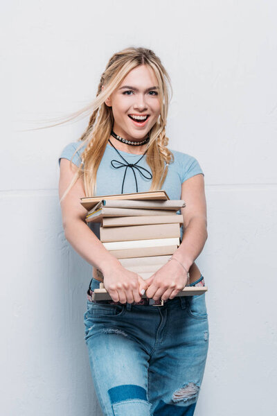 young smiling caucasian girl holding books and looking at camera