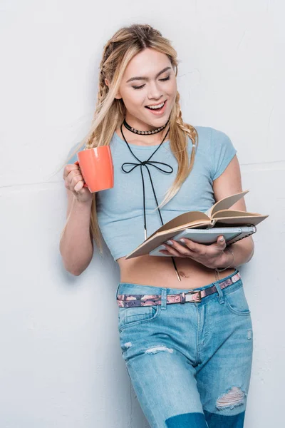 Kaukasisches blondes Mädchen trinkt Kaffee und liest Bücher mit Gesichtsausdruck — Stockfoto