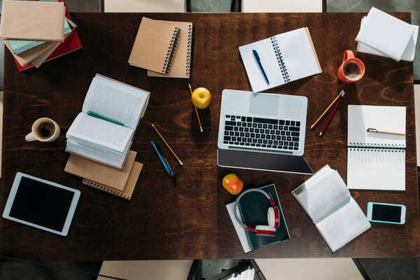 Vue de dessus des appareils numériques avec des cahiers et des tasses à café avec des pommes sur la table — Photo