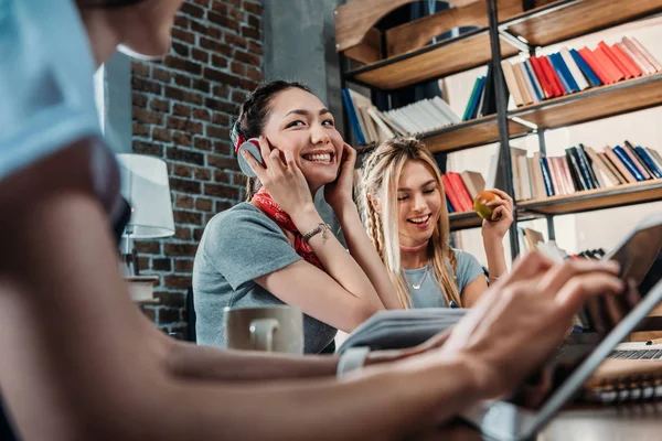 Recortado disparo de mujer joven usando tableta digital y hermosos amigos sonrientes sentados detrás — Foto de Stock