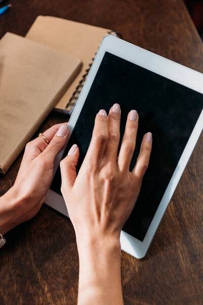 cropped shot of woman using digital tablet with blank screen on tabletop