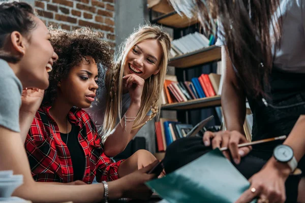 Des jeunes femmes gaies parlent et étudient ensemble à la bibliothèque — Photo