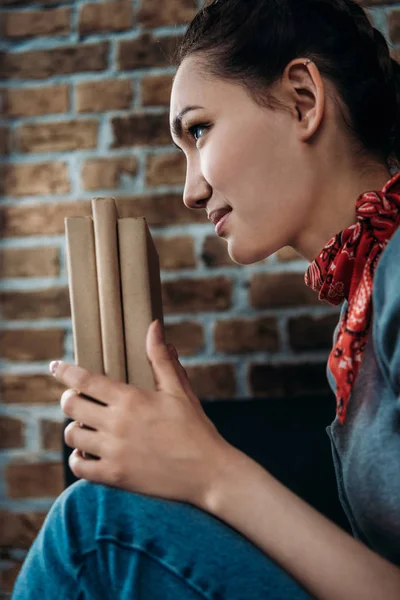 Profile portrait of beautiful young asian woman holding books and looking away — Free Stock Photo