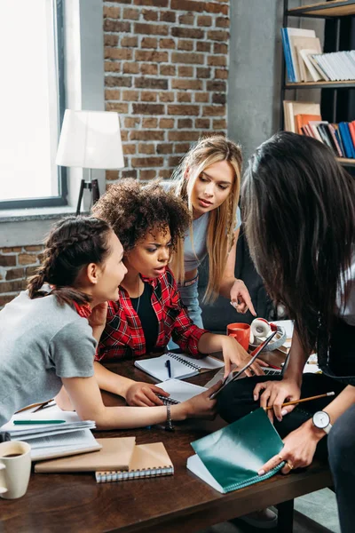 Mulheres multiétnicas jovens olhando para tablet digital enquanto trabalhava no escritório em casa Imagem De Stock