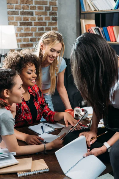 Jovem sorrindo mulheres multiétnicas olhando para tablet digital enquanto trabalhava no escritório em casa Fotografias De Stock Royalty-Free