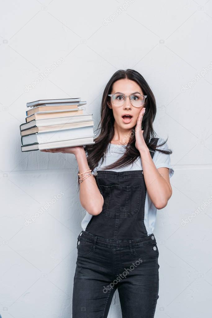 astonished caucasian student holding books with facial expression