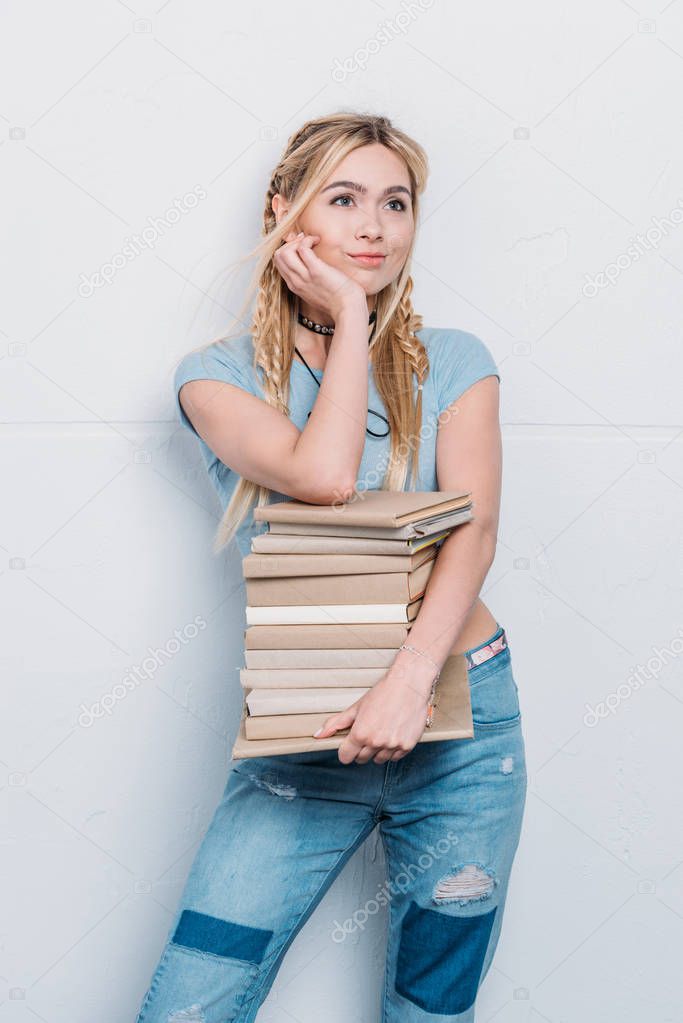 young pensive caucasian girl holding books and looking away