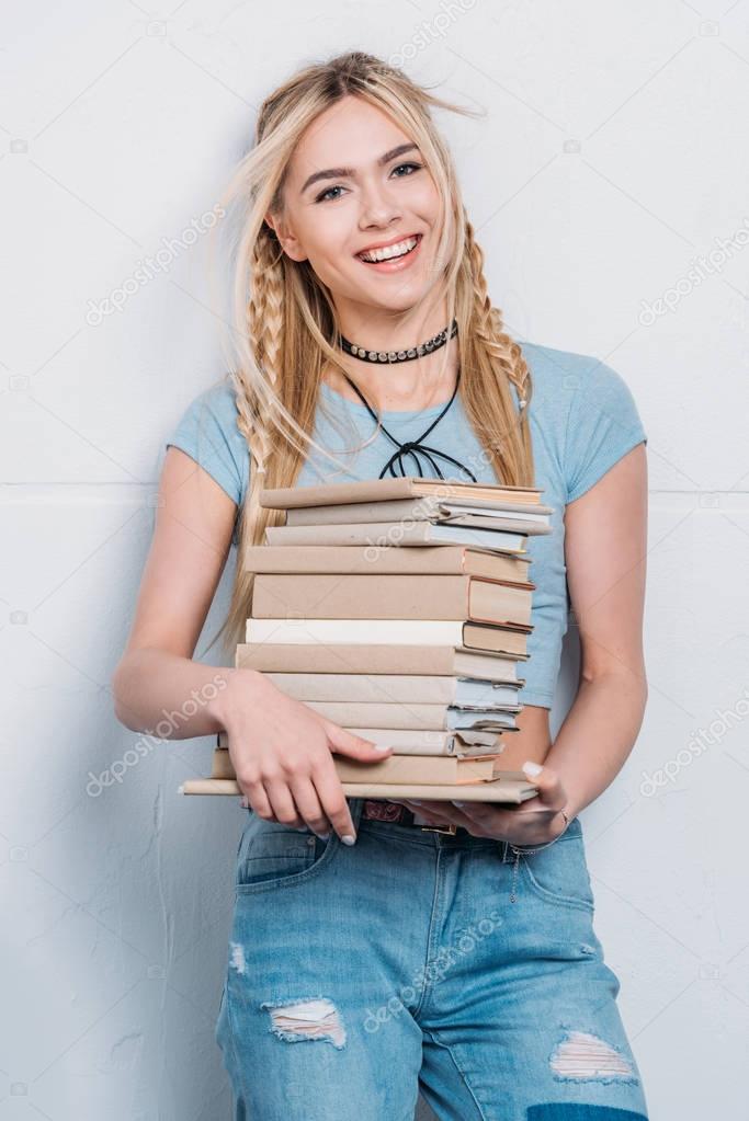 young smiling caucasian woman holding books and looking at camera