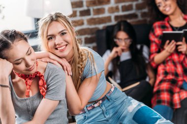 Gülümseyen genç kadınlar birlikte arkasında kitap okuma arkadaşlarıyla eğleniyor