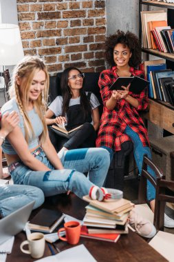 Smiling young women sitting and studying together with books clipart