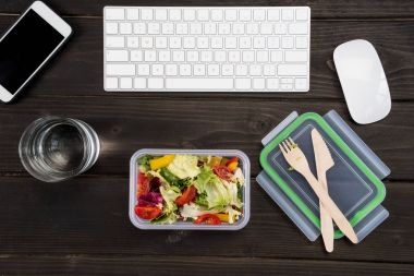Ahşap masa üzerinde akıllı telefon, bilgisayar klavye ve bilgisayar fare taze salata ile Üstten Görünüm. 