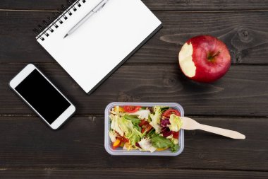 Apple, defter ve smartphone ile organik salata üstten görünüm ahşap tablo