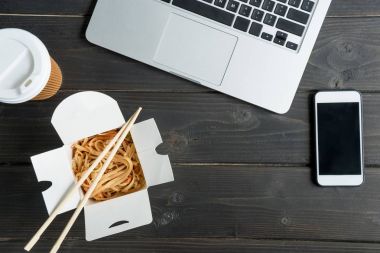 noodle yemek çubukları ile ve laptop üzerinde ahşap masa kahve ile Üstten Görünüm