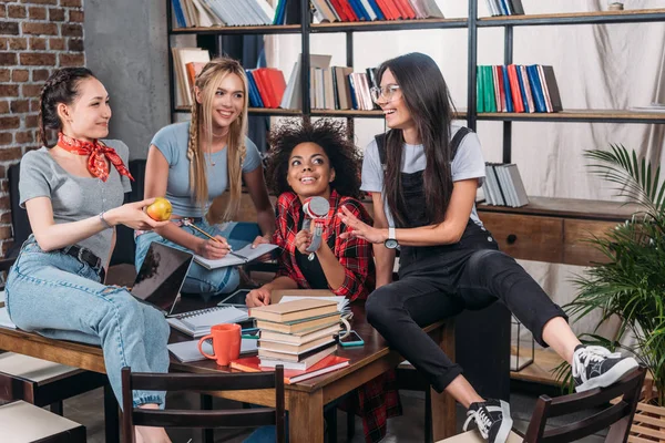Uśmiechnięta młoda kobieta studia razem i rozmowy przy stole z książek — Zdjęcie stockowe