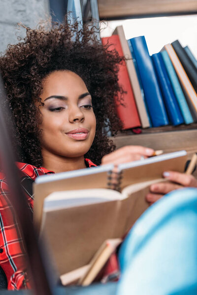 Attractive young african american student studying with books and textbooks 