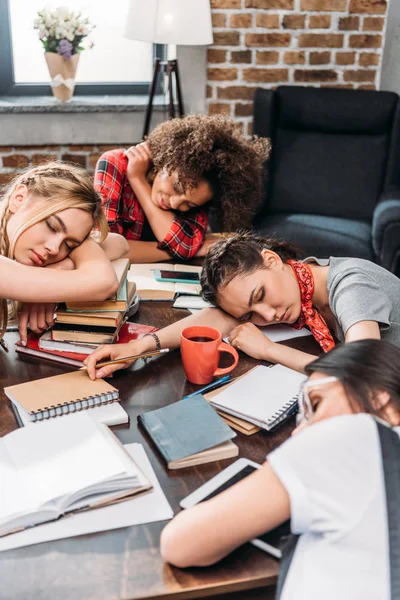 Уставшие молодые студенты спят за столом с ноутбуками и цифровыми устройствами — стоковое фото