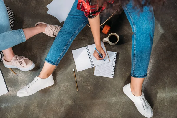 Recorte de estudiantes sentados juntos, estudiando y tomando notas en cuadernos — Foto de Stock