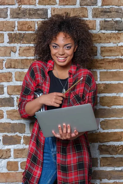 Joven afroamericana mujer sonriendo y sosteniendo portátil - foto de stock