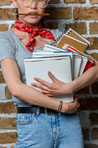 Cropped shot of casual woman in glasses holding books — Stock Photo