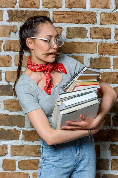 Portrait of young asian student in glasses holding books — Stock Photo