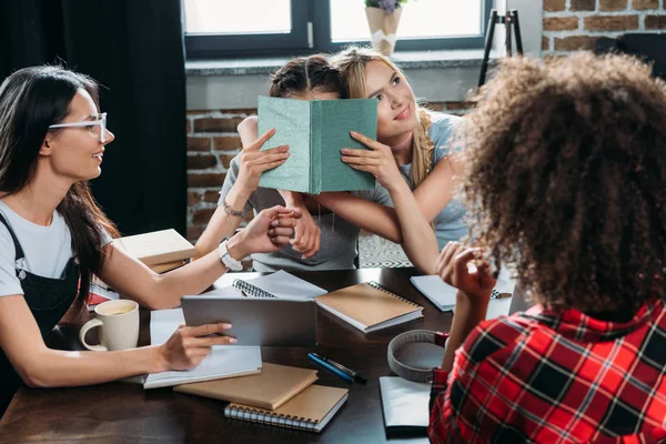 Niñas multiétnicas que trabajan mientras están sentadas en la mesa en casa oficina - foto de stock