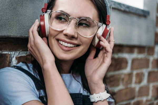 Portrait en gros plan d'une jeune femme souriante portant des lunettes d'écoute et détournant les yeux — Photo de stock