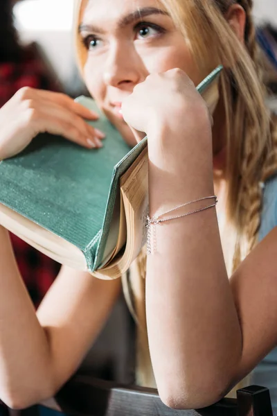Close up portrait of caucasian girl holding book and looking away — Stock Photo
