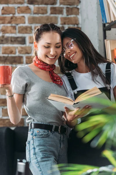 Jeunes étudiants attrayants avec livre et tasse étudiant ensemble et souriant — Photo de stock
