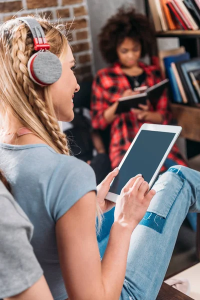 Smiling young woman in headphones using digital tablet with blank screen — Stock Photo