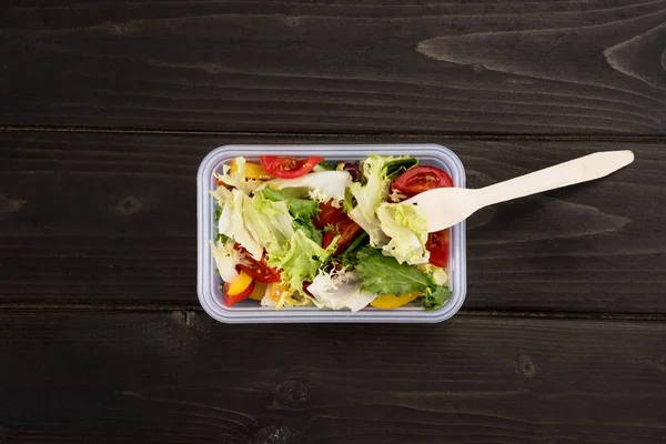 Ansicht von gesundem Salat in Plastikbox auf Holztisch — Stockfoto